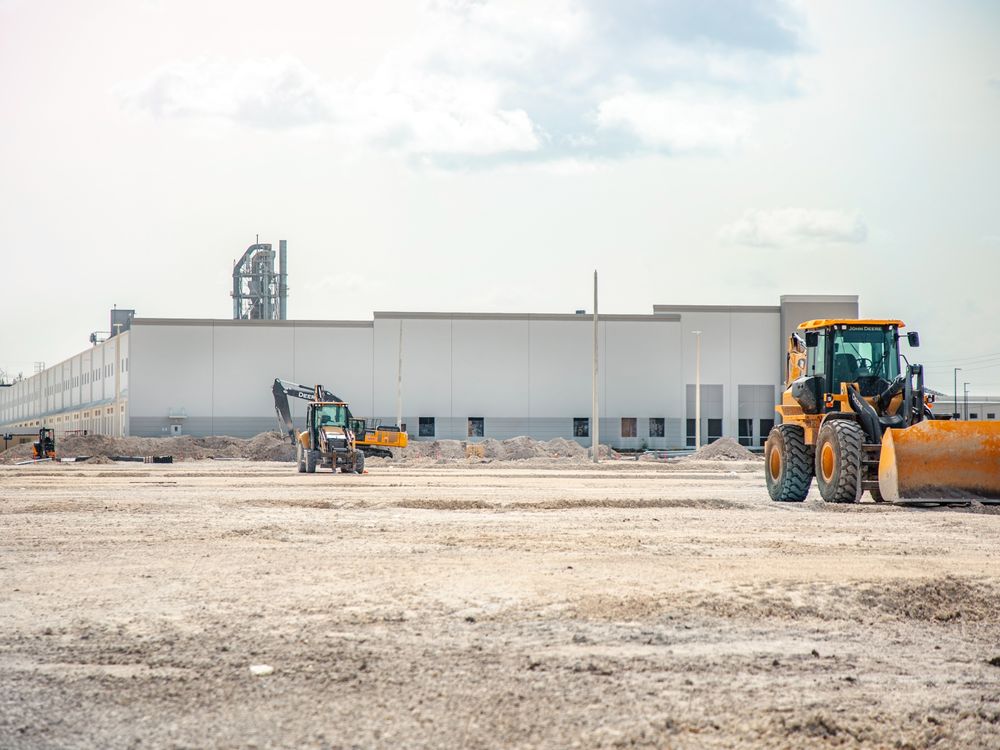 Large industrial shed building under construction with earthmoving equipment on the graded site